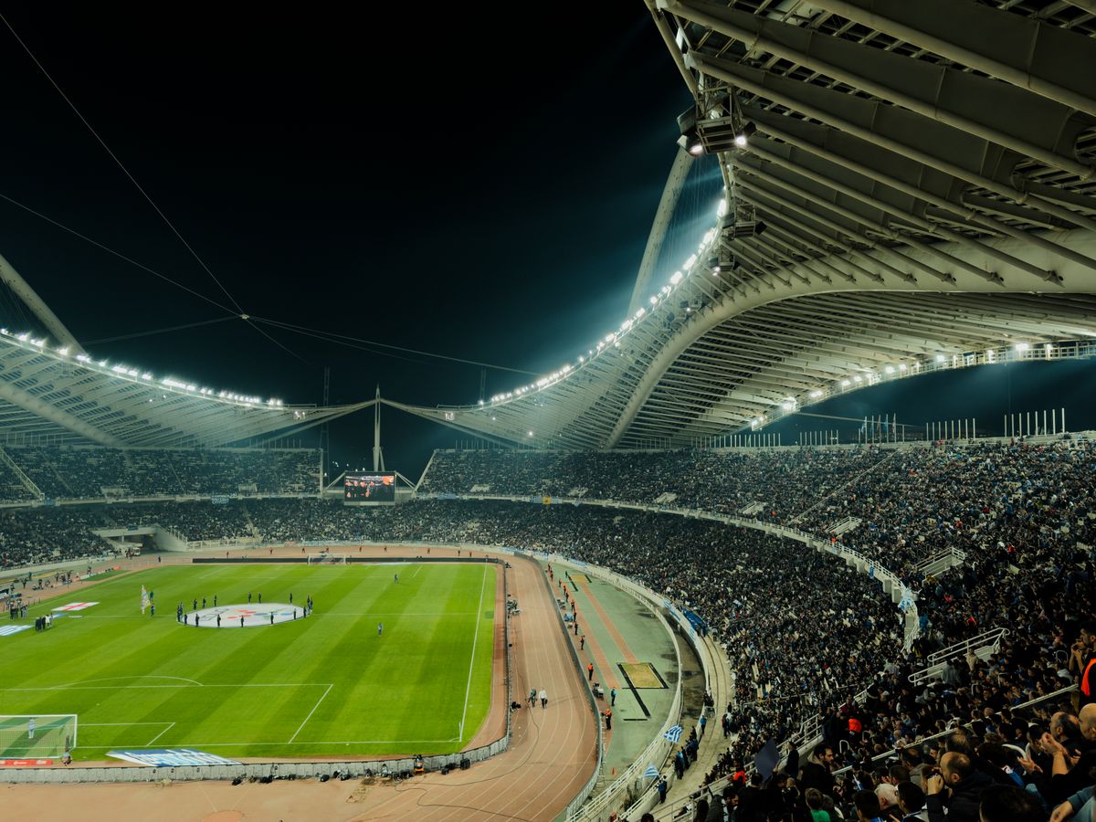 An illuminated football stadium at night with a crowd